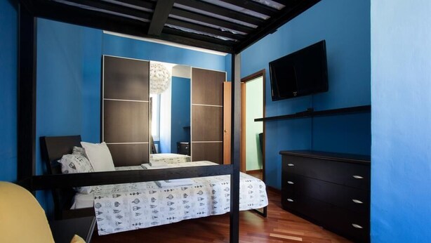 A bedroom with a bed, a TV mounted on the wall, and a wardrobe. - Colorful apt in Milano (Milan)