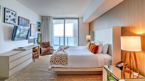 Une chambre d’hôtel moderne dotée d’un grand lit, d’un bureau, d’une chaise, d’une télévision et offrant une vue sur la ville.