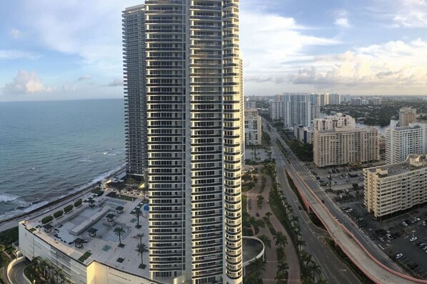 Un edificio moderno y alto, con fachada curva, situado cerca de la costa y vistas al océano.