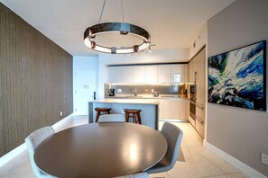 Una cocina moderna con una isla central, taburetes de bar y una mesa de comedor.