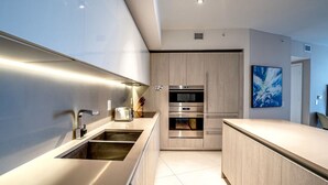 Une cuisine moderne dotée d’appareils électroménagers en acier inoxydable, de meubles en bois et d’un design minimaliste.