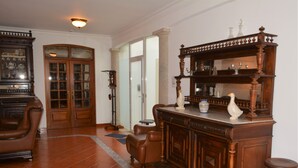 A spacious living room with a large wooden cabinet, leather armchairs, and a dining table. - Casal dos Cantos Poente (Quinta do Anjo)