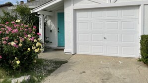 Une maison blanche avec une porte turquoise et une porte de garage blanche.