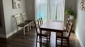 Un coin repas avec une table et des chaises en bois, un lustre et une plante en pot.