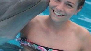 Una persona en una piscina con un delfín.