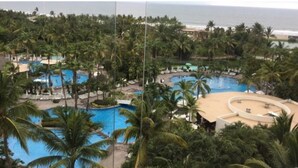 Un resort con varias piscinas rodeado de palmeras y vistas a la playa.