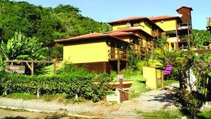Un edificio amarillo con techo rojo, rodeado de follaje y un letrero que dice 'Baras Fruit House'.