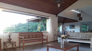 Una habitación amplia con un banco de madera, una mesa y vistas a zonas verdes.