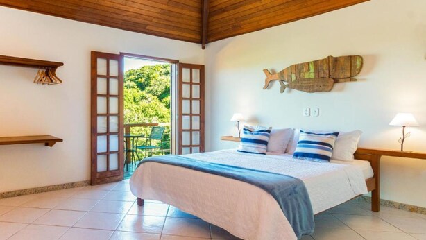 Un dormitorio con cama, techo de madera, vista a través de una puerta abierta y un adorno de pez colgado en la pared.