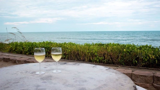 Two glasses of white wine on a round table with a view of the sea and sky.