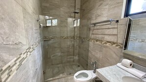 Ein modernes Badezimmer mit einer Duschkabine, einer Toilette und einem Waschbecken mit Spiegel darüber.