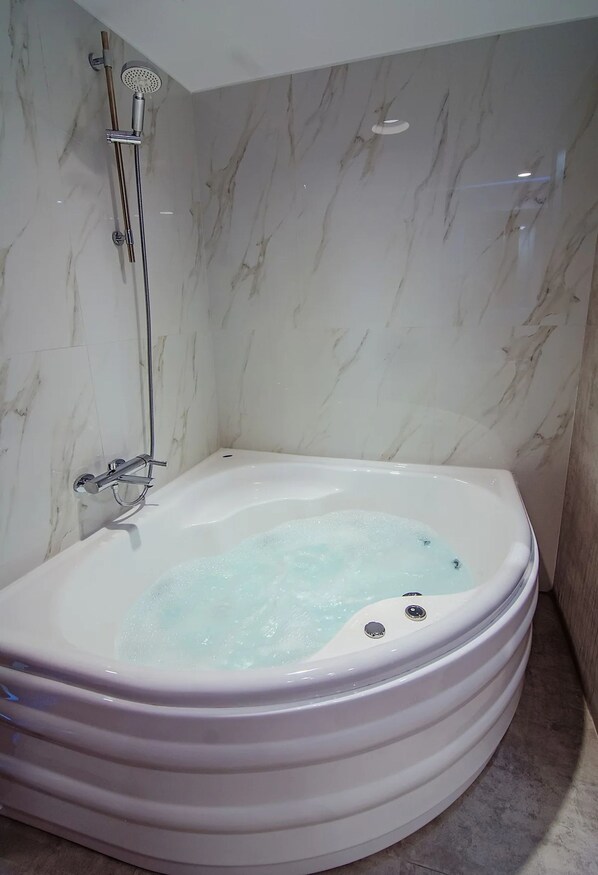 A modern bathroom with a marble wall, a freestanding bathtub, and a showerhead.