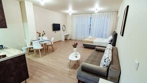 Een moderne woonkamer met een bank, eettafel en televisie.