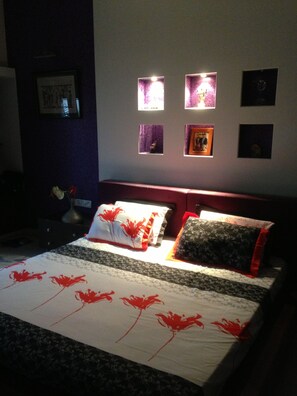 Cozy retreat with a neatly made bed, picture frames, and a functional nightstand.