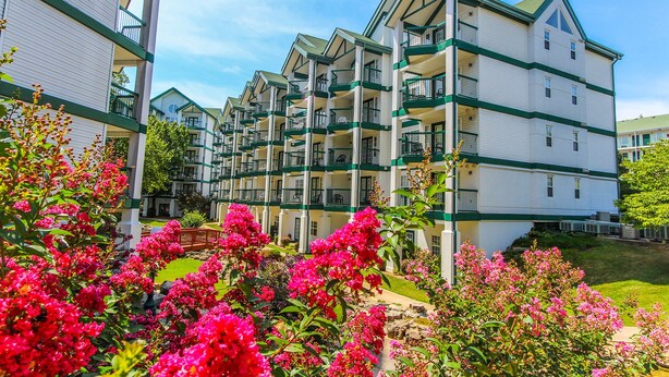 A multi-story hotel with balconies, a garden with pink flowers, and a clear blue sky. - NEW! Christmas week in Branson 2 BR/3 BA/sleeps 8, indoor pool, 1486 sq ft (Branson)