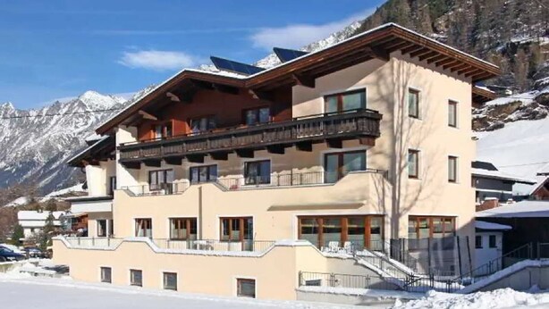 A multi-story hotel with balconies, a ski slope in the background, and snow-covered surroundings. - Alpenheim Joergele (Soelden)