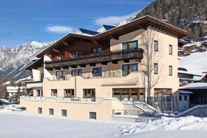 A multi-story hotel with balconies, a ski slope in the background, and snow-covered surroundings. - Alpenheim Joergele (Soelden)