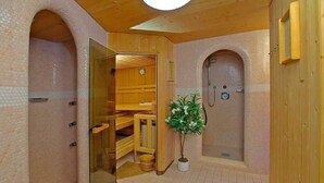 A wooden interior with a sauna, a shower, and a small plant. - Alpenheim Joergele (Soelden)