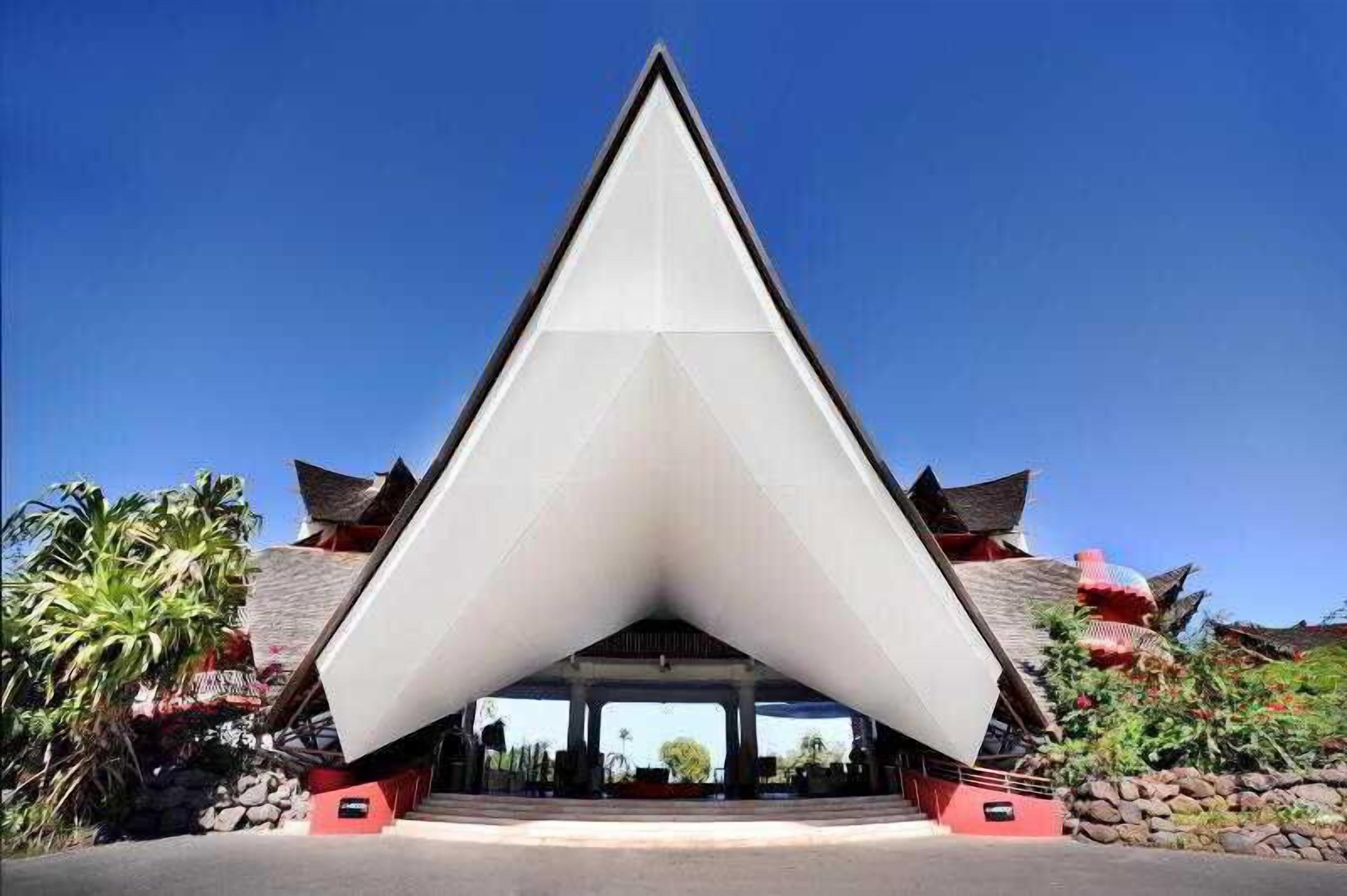 Un bâtiment moderne doté d’une structure de toit triangulaire et d’éléments architecturaux traditionnels.