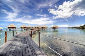 A wooden pier leading to overwater bungalows with thatched roofs. - Tahiti Ia Ora Beach Resort (Punaauia)