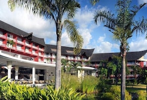 A hotel with multiple floors, outdoor seating, and palm trees. - Tahiti Ia Ora Beach Resort (Punaauia)