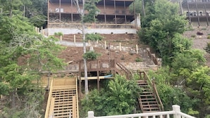 A multi-story building with a wooden deck and stairs leading up to it, surrounded by trees. - Lakefront Gem, Mtn views, dock + HOT TUB (Blairsville)