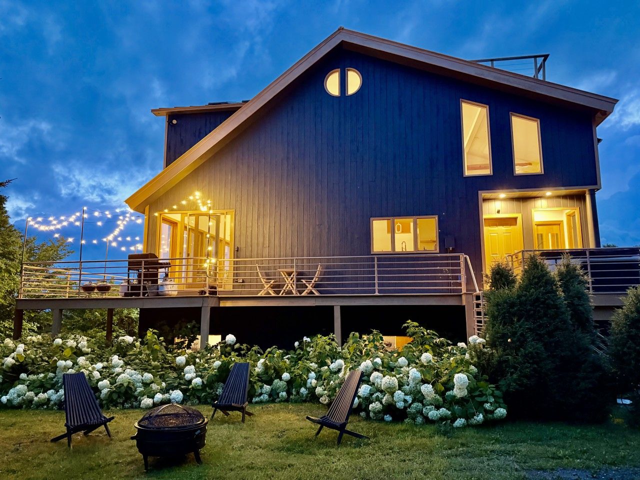 A modern two-story house with a balcony, a fireplace, and a well-maintained garden.