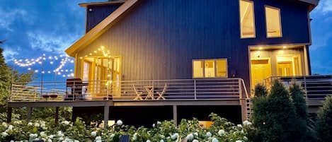 A modern two-story house with a balcony, a fireplace, and a well-maintained garden.