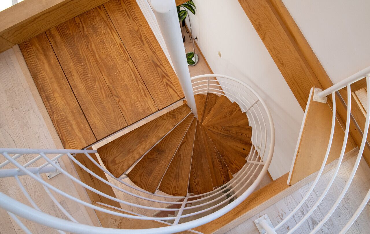 A spiral staircase with wooden steps and white metal railings.