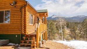 A log cabin with a porch, a fire hydrant, and a mountainous backdrop. - Mountain Sunrise Cabin with breathe taking views. (Divide,)
