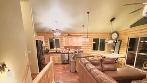 A modern kitchen with wooden cabinets, a central island, and pendant lighting. - Mountain Sunrise Cabin with breathe taking views. (Divide,)