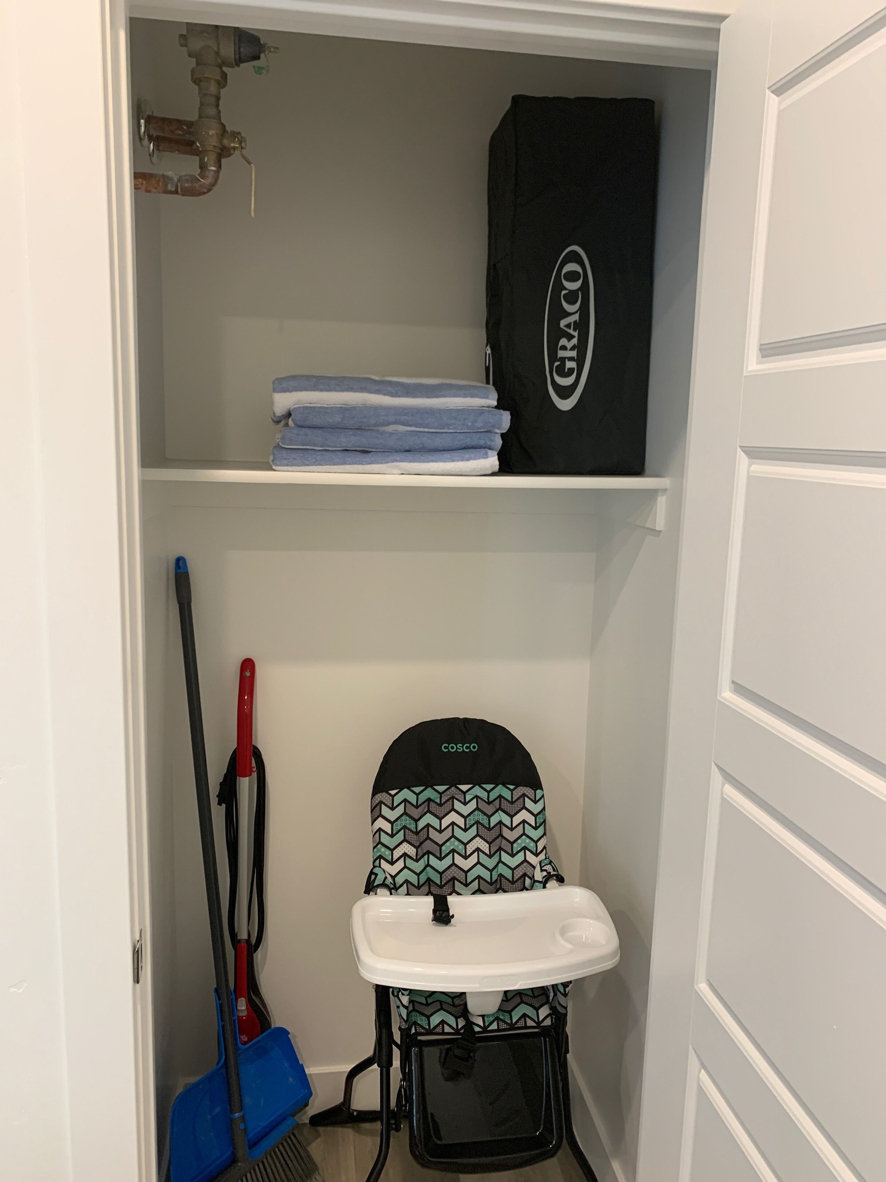 A small storage closet with shelves, a baby stroller, a mop, and cleaning supplies.