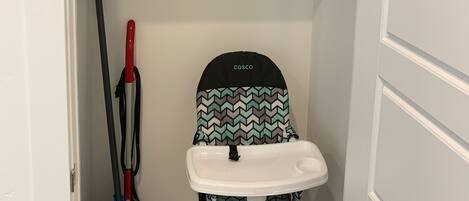 A small storage closet with shelves, a baby stroller, a mop, and cleaning supplies.