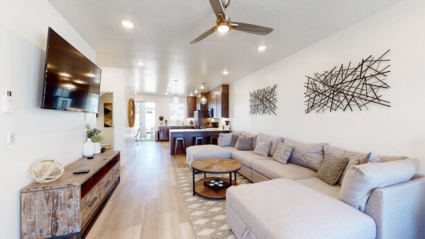 A modern living room with a large sofa, a coffee table, and a TV mounted on the wall.