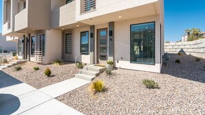 A modern multi-story building with a flat facade, large windows, and a gravel driveway.
