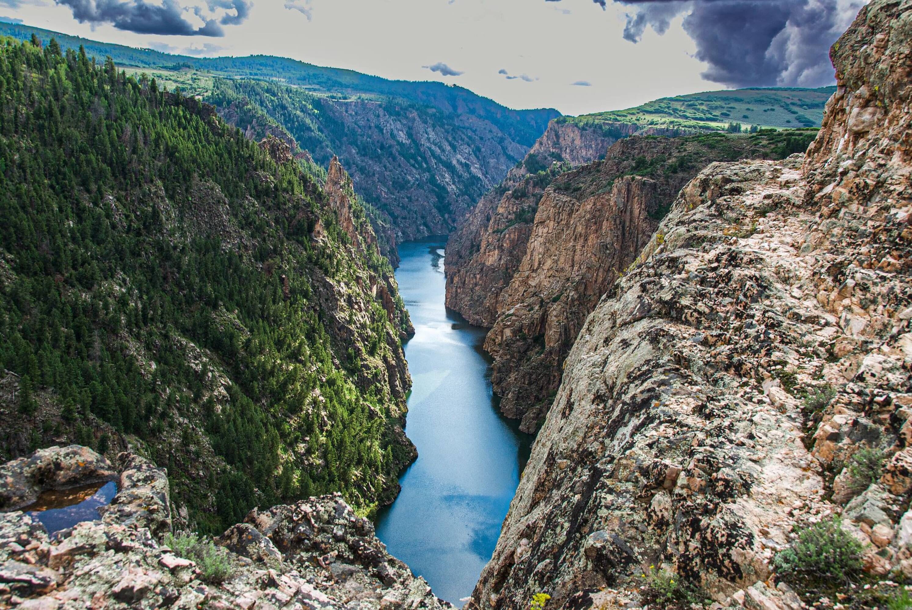 A canyon with a river, surrounded by forested hills.