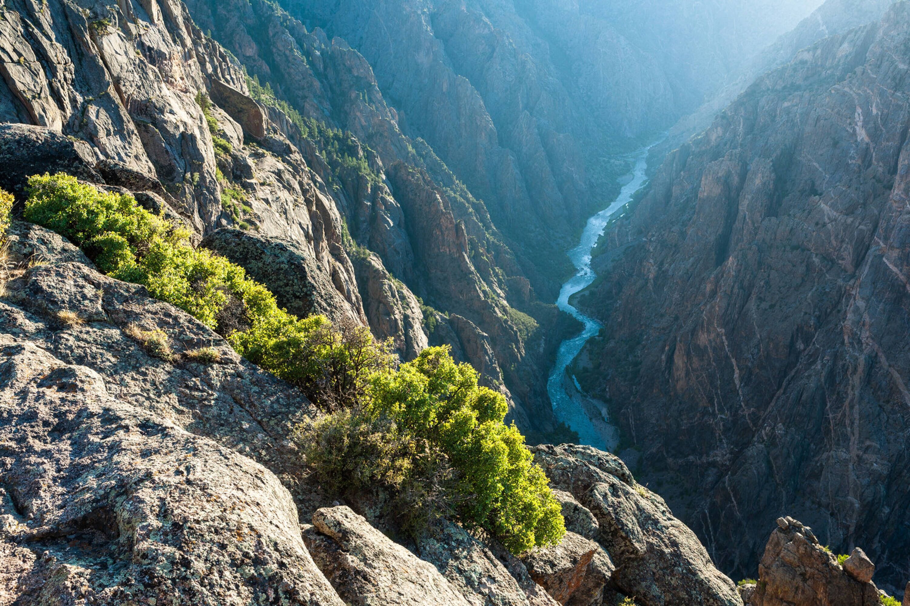 A canyon with a river, rocky terrain, and sparse vegetation.