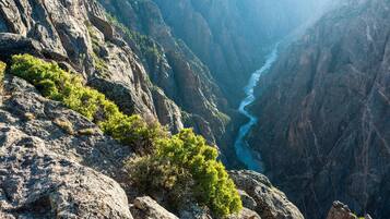 A canyon with a river, rocky terrain, and sparse vegetation.