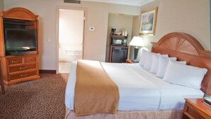 A hotel room with a bed, a wooden dresser, a television, a desk, and a microwave. - Red Arrow Inn & Suites, a Travelodge by Wyndham (Montrose)