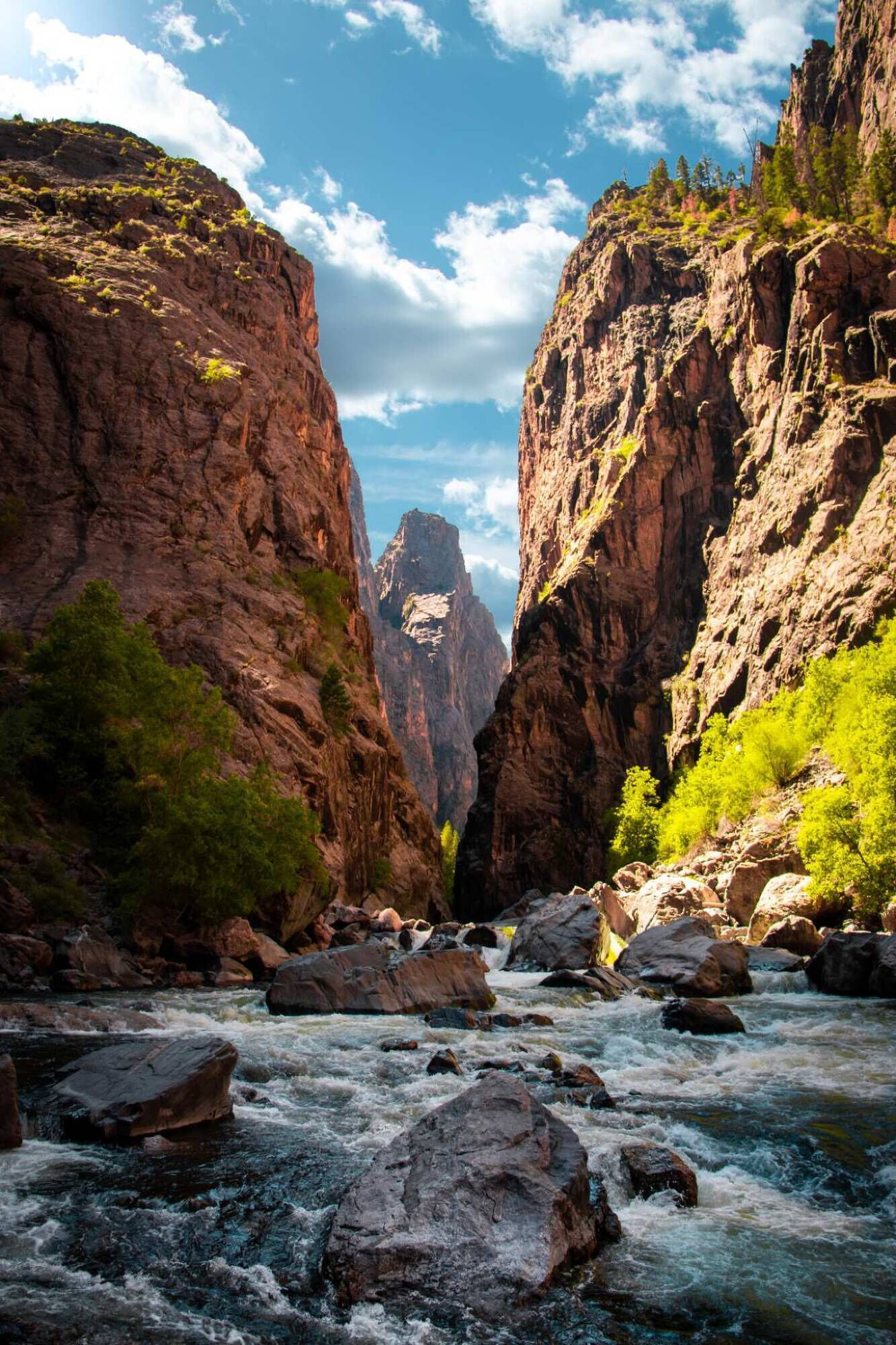 Un cañón con un río que lo atraviesa, rodeado de acantilados rocosos y vegetación.