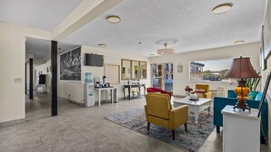 A modern living room with a dining area, a kitchen, and a large window providing a view of the outside. - Red Arrow Inn & Suites, a Travelodge by Wyndham (Montrose)