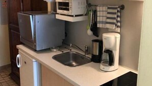A compact kitchenette with a microwave, toaster, coffee maker, and a small sink. - Appartementhaus Alpina (Bad Hofgastein)