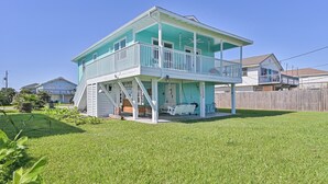 A two-story house with a balcony and a covered porch area. - Sea Shed-Big yard in Jamaica Beach-Pet Friendly! (Jamaica Beach)