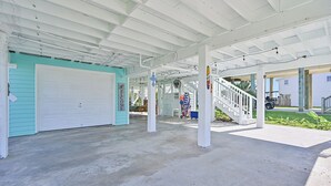 A covered outdoor area with a garage door, a staircase, and a sign that reads "WELCOME". - Sea Shed-Big yard in Jamaica Beach-Pet Friendly! (Jamaica Beach)
