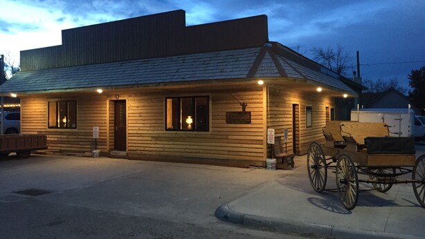 A wooden building with a sloped roof, a porch with benches, and a carriage. - ADULTS 25 and older, Creekside Vacation Rental Suite 2,  Downtown, CITY APPROVE (Buffalo)