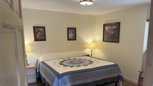 A bedroom with a bed, two bedside lamps, and framed artwork on the walls. - ADULTS 25 and older, Creekside Vacation Rental Suite 2,  Downtown, CITY APPROVE (Buffalo)