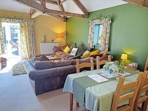 A cozy living room with a sofa, a dining table, and a green wall.