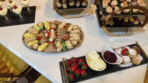 Une table de buffet proposant divers plats, notamment des sandwichs, des salades et des desserts.