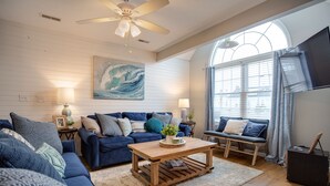 A living room with a blue sofa set, a wooden coffee table, and a large window with curtains. - Lake Erie Getaway Near The Beach & Cedar Point (Huron,)