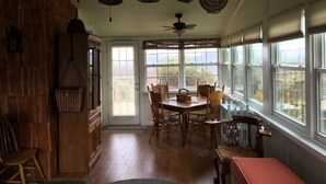 A dining area with a wooden table and chairs, a bench, and a view of the outdoors through large windows. - Air Bellows Gap Retreat (Sparta)